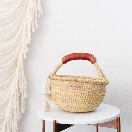 Plum+Sparrow Cognac Handle Small Market Basket on a white stool against a light gray wall.