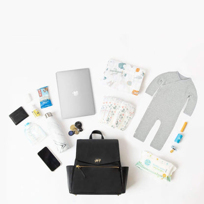 Collection of baby items including a black backpack, diaper, and baby clothes on a white background