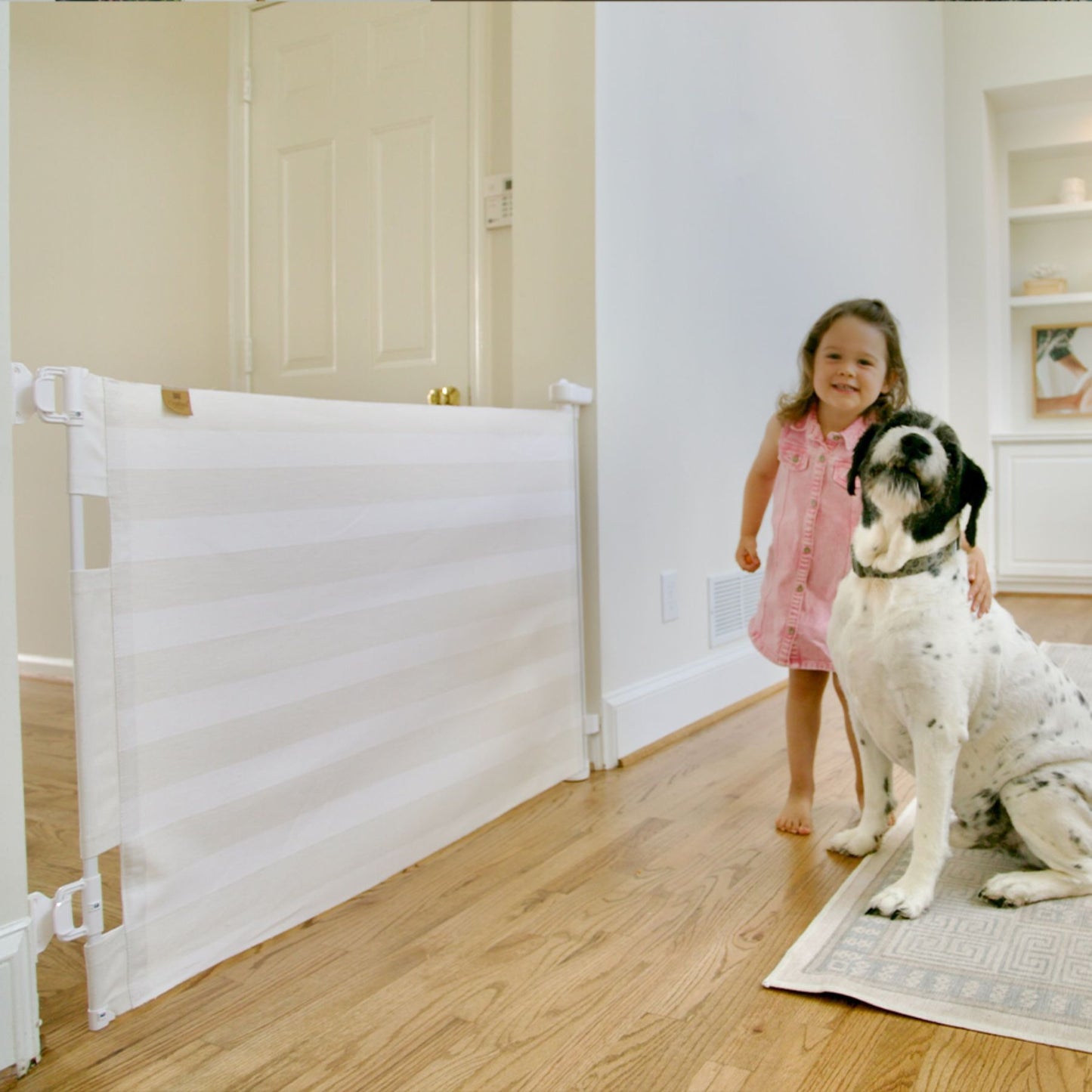 Child in a pink dress standing next to a dog near Crypton® Fabric Baby & Pet Safety Gate - Cloud Grey in a home setting.