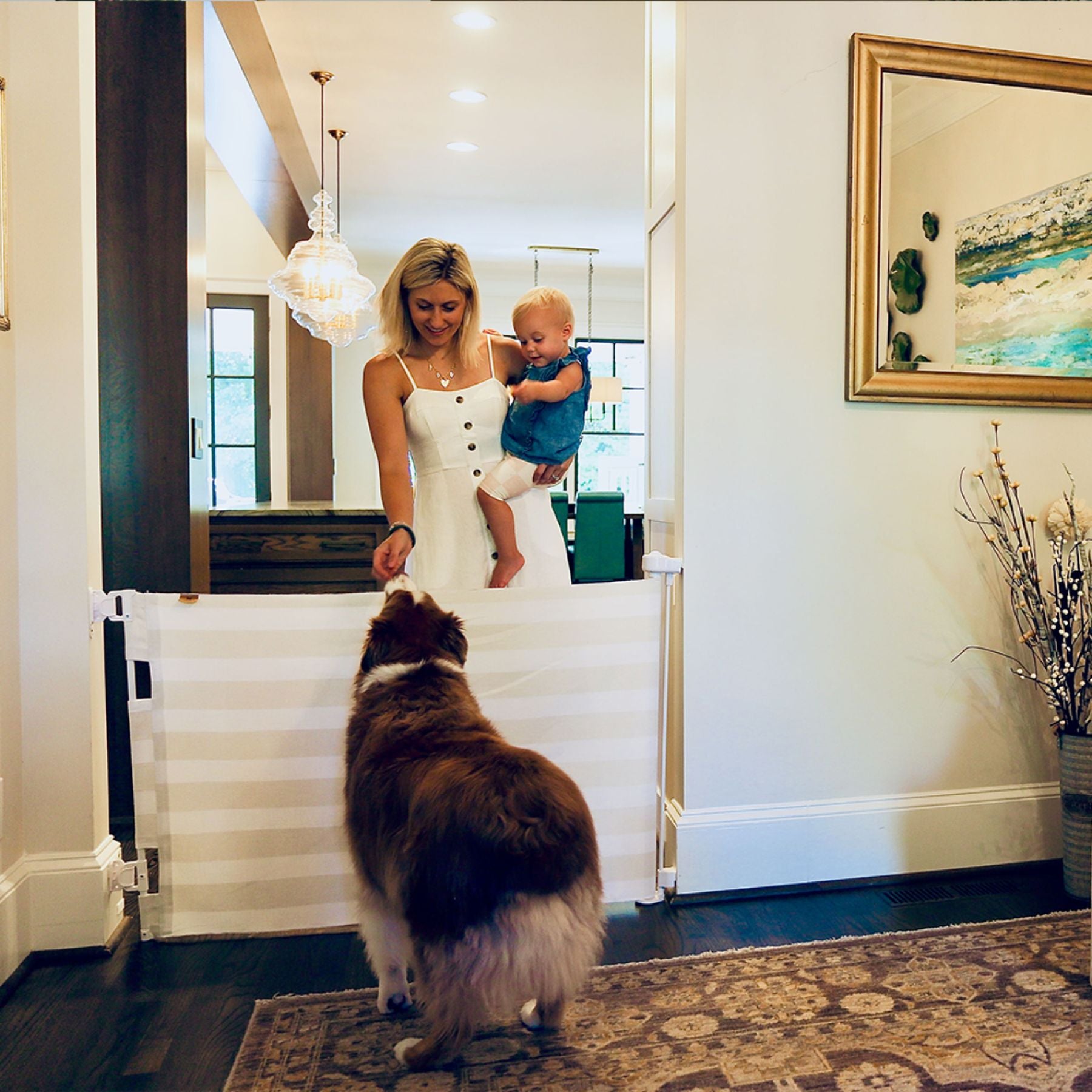 Woman holding a child and a dog standing on Crypton® Fabric Baby & Pet Safety Gate - Dove in a home setting.