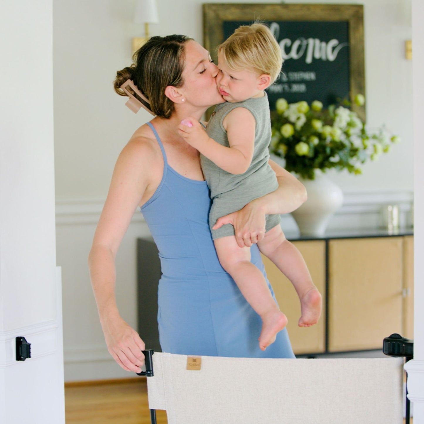 Woman in a blue dress holding a child in a home setting