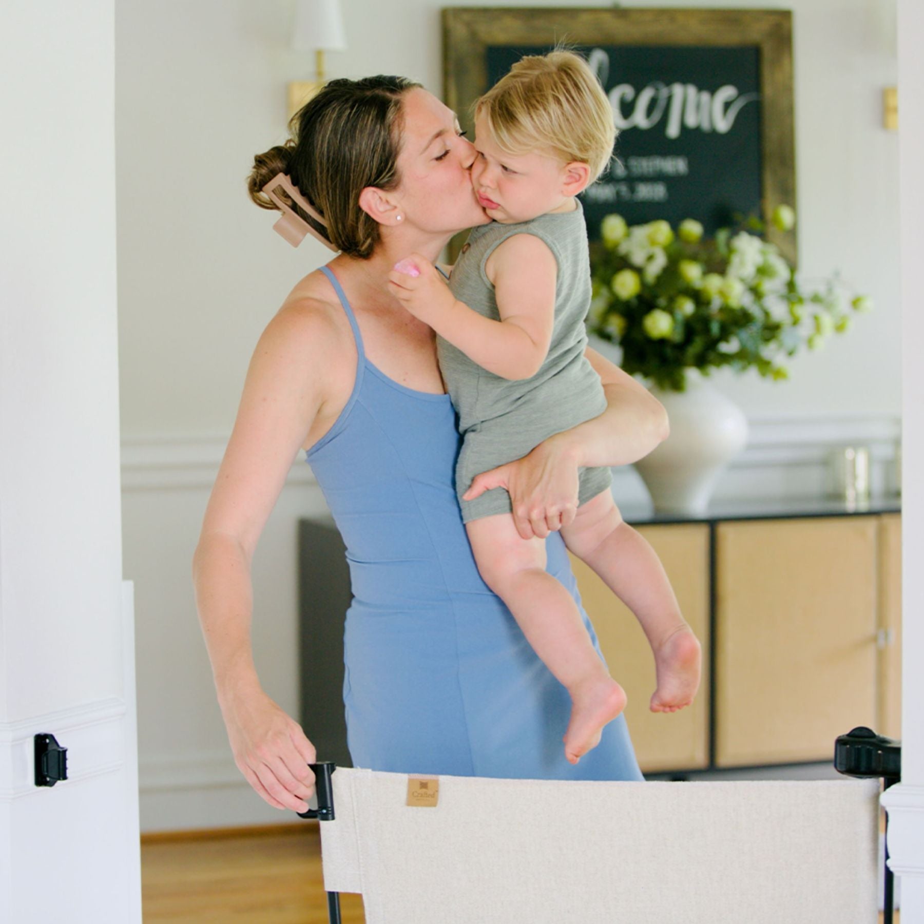 Woman in a blue dress holding a child in a home setting