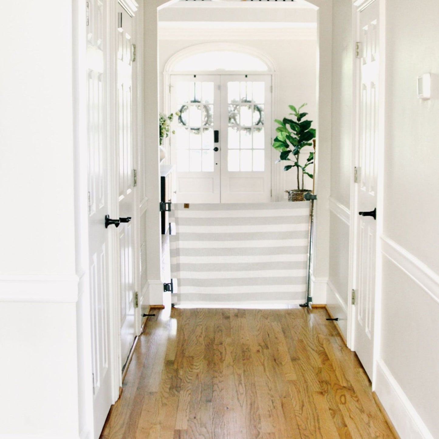 Hallway with Crypton® Fabric Baby & Pet Safety Gate - Oxide, white walls, and a staircase leading to a white door.