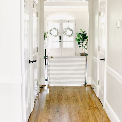 Hallway with Crypton® Fabric Baby & Pet Safety Gate - Oxide, white walls, and a staircase leading to a white door.