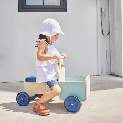Child riding on PlanToys Delivery Bike - Orchard on a sunny day