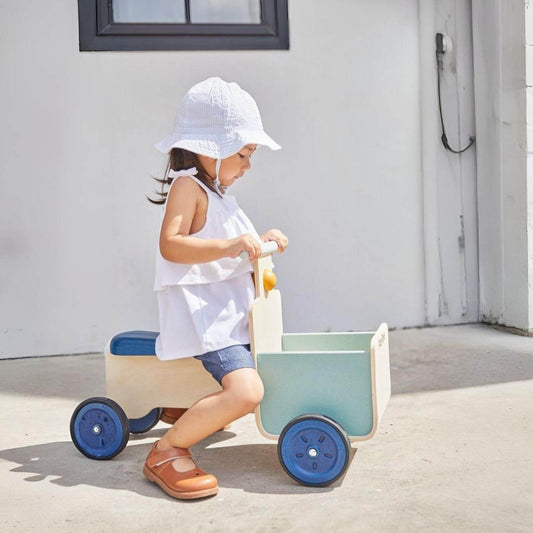 Child riding on PlanToys Delivery Bike - Orchard on a sunny day