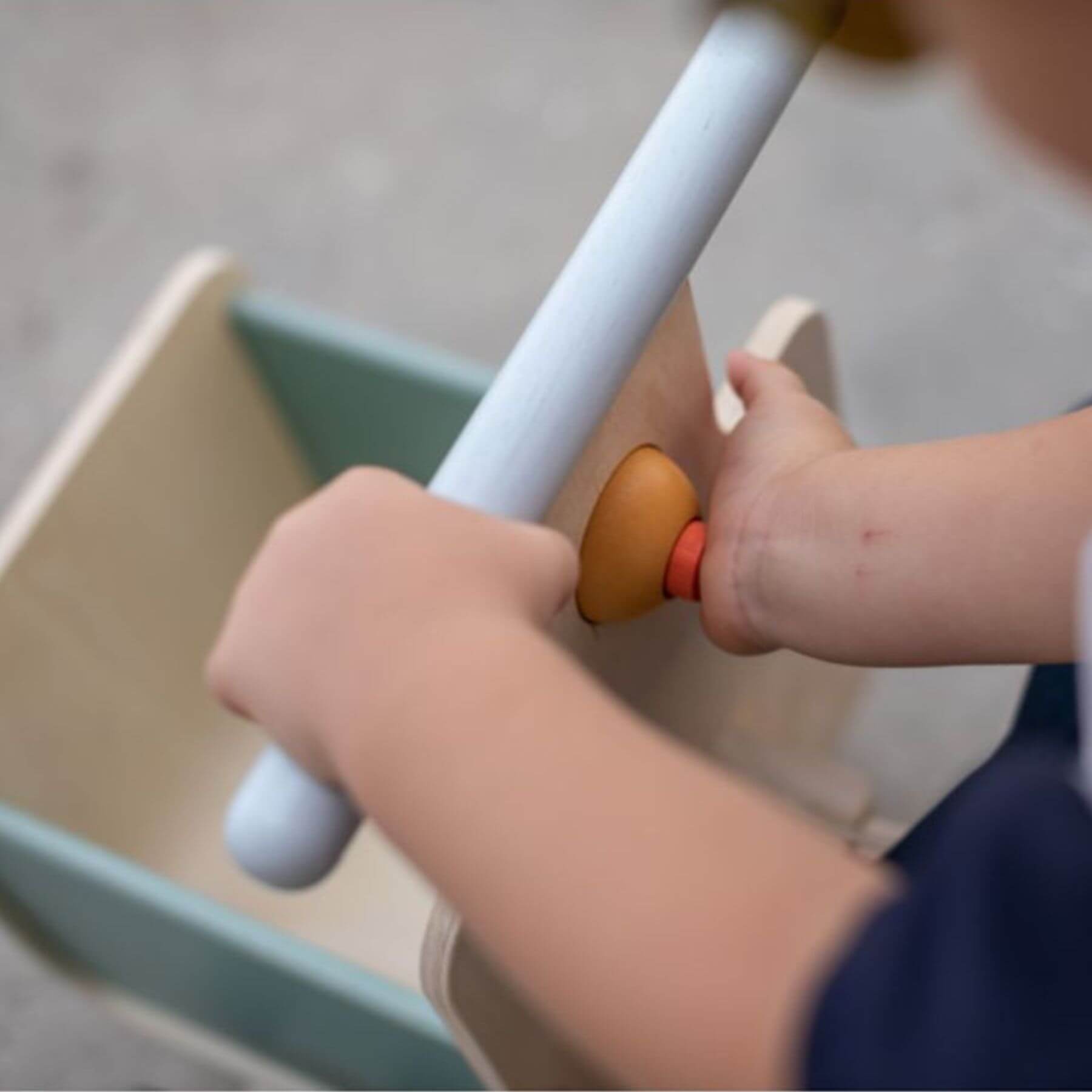 Child's hand holding PlanToys Delivery Bike - Orchard