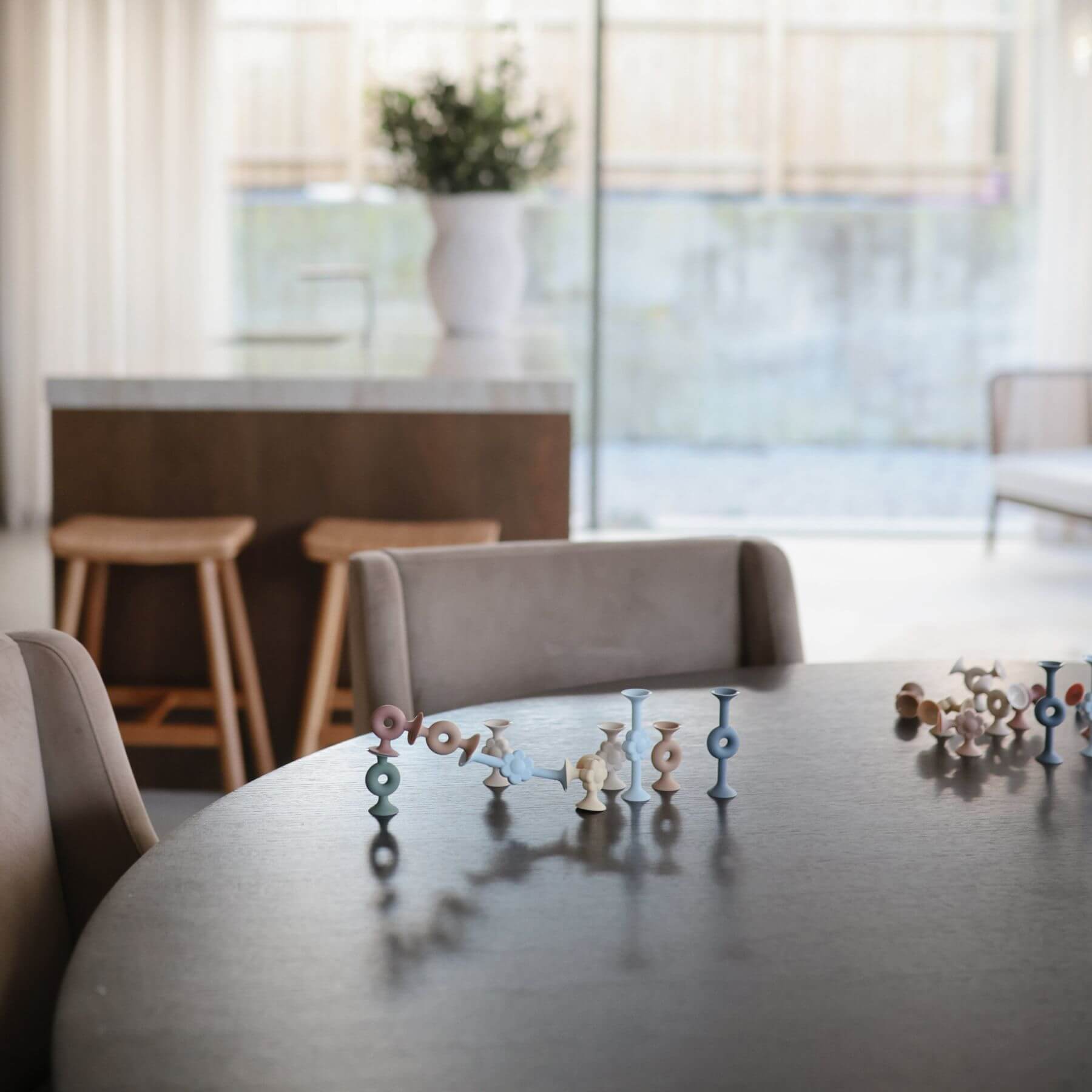 Mushie Donut Silicone Suction Builders on a table with a modern interior background