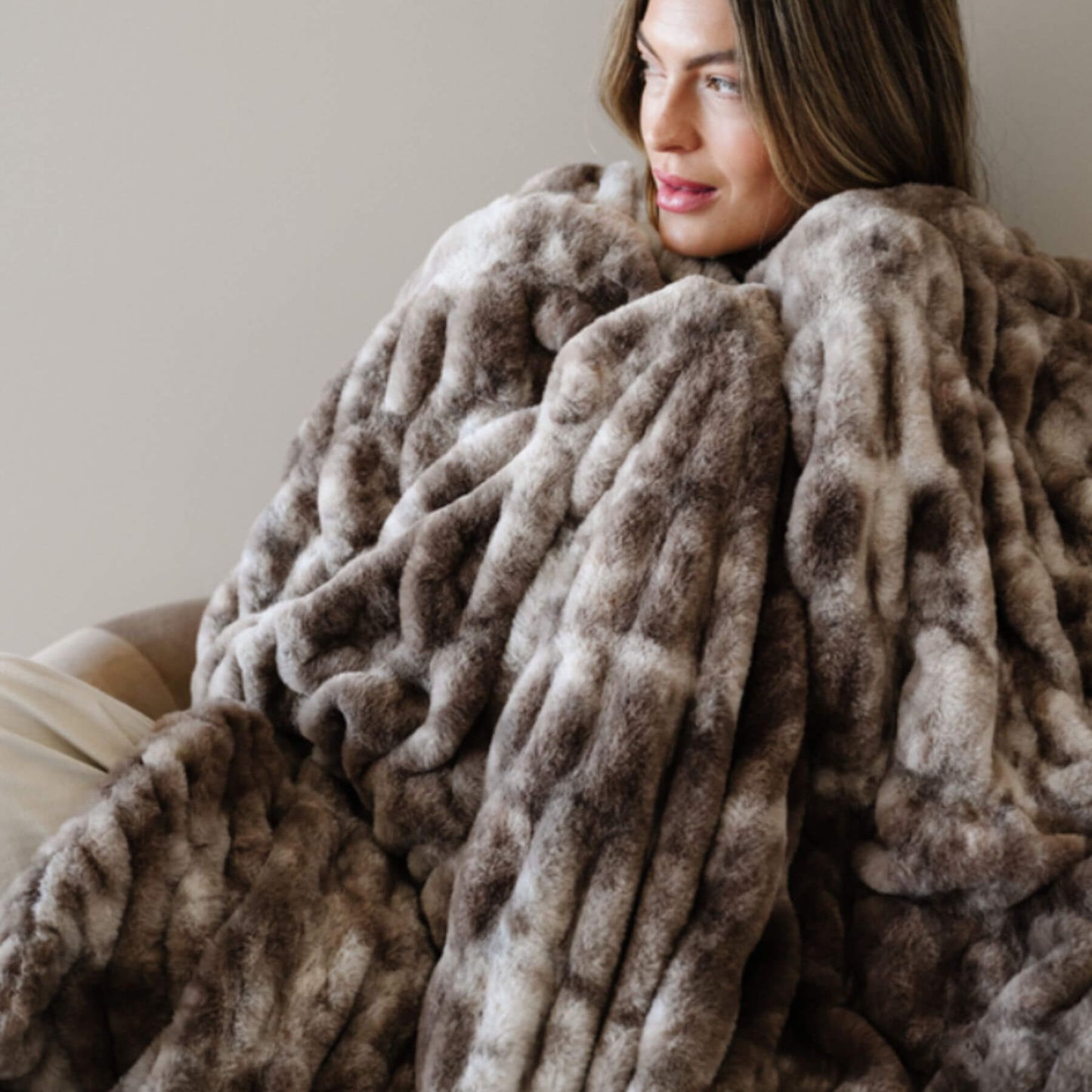 Woman wrapped in Saranoni Double Ruched Faux Fur Throw Blankets Chocolate against a neutral background