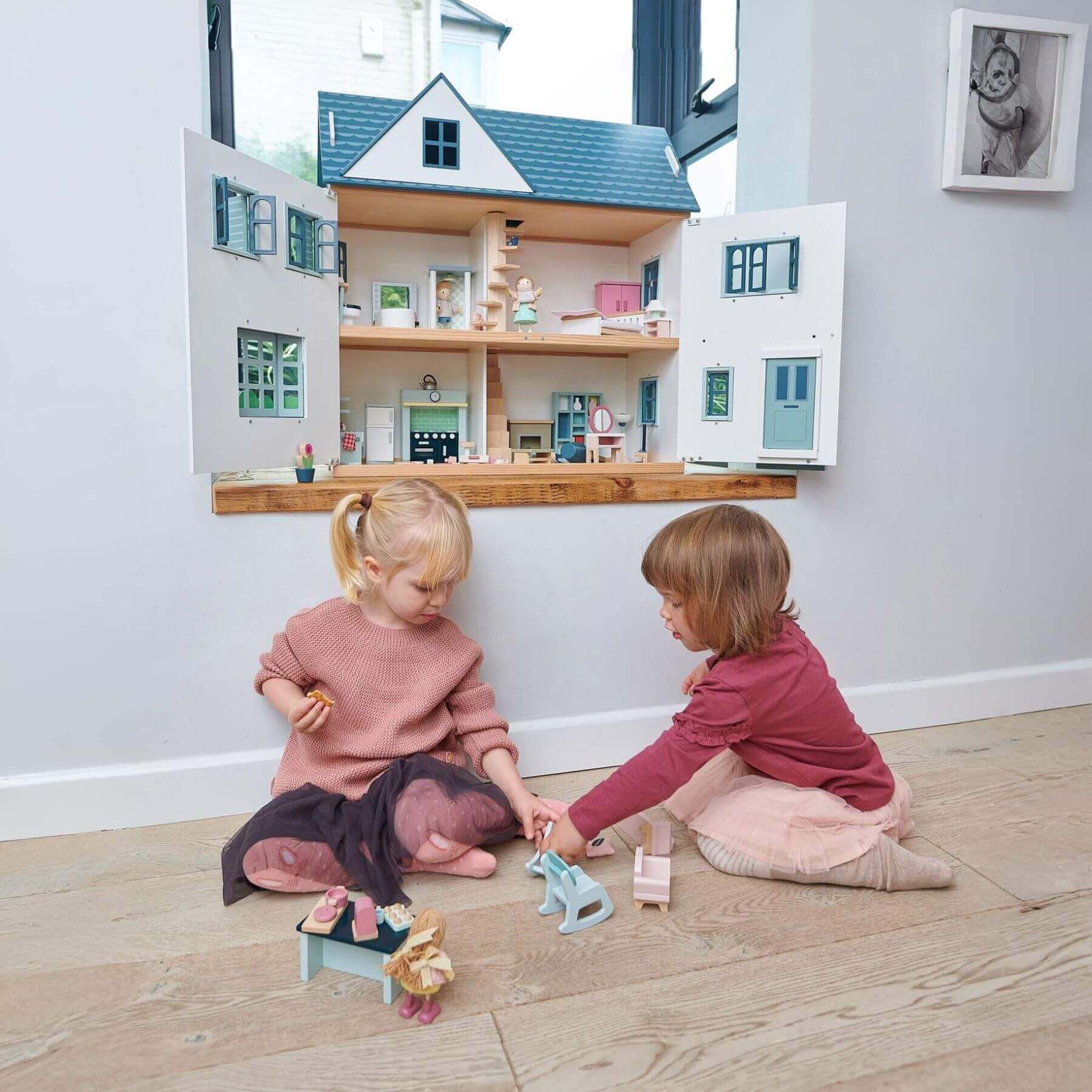 Two children playing with Tender Leaf Dovetail House in a room.