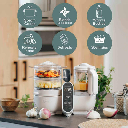 Babymoov Duo Meal Station Baby Food Maker on a kitchen counter with icons indicating its features.