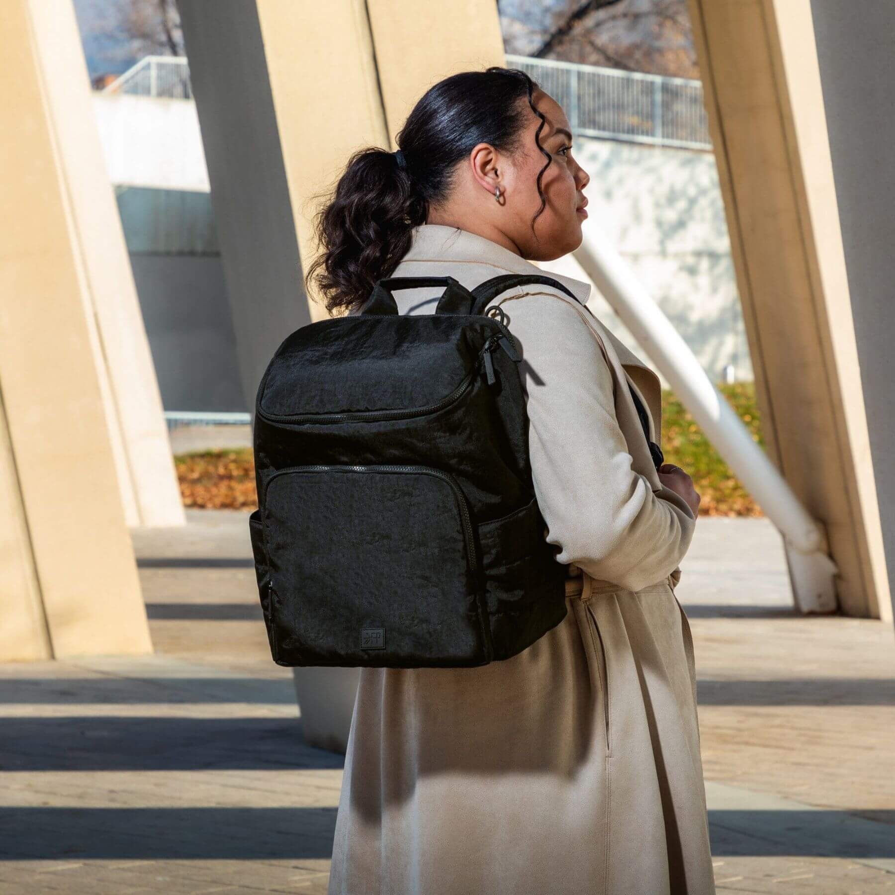 Person wearing Ebony Zurich Diaper Bag outdoors near a building