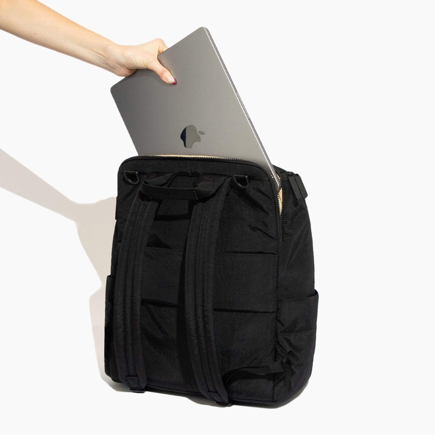 Ebony Zurich Diaper Bag with a laptop being placed into it on a white background
