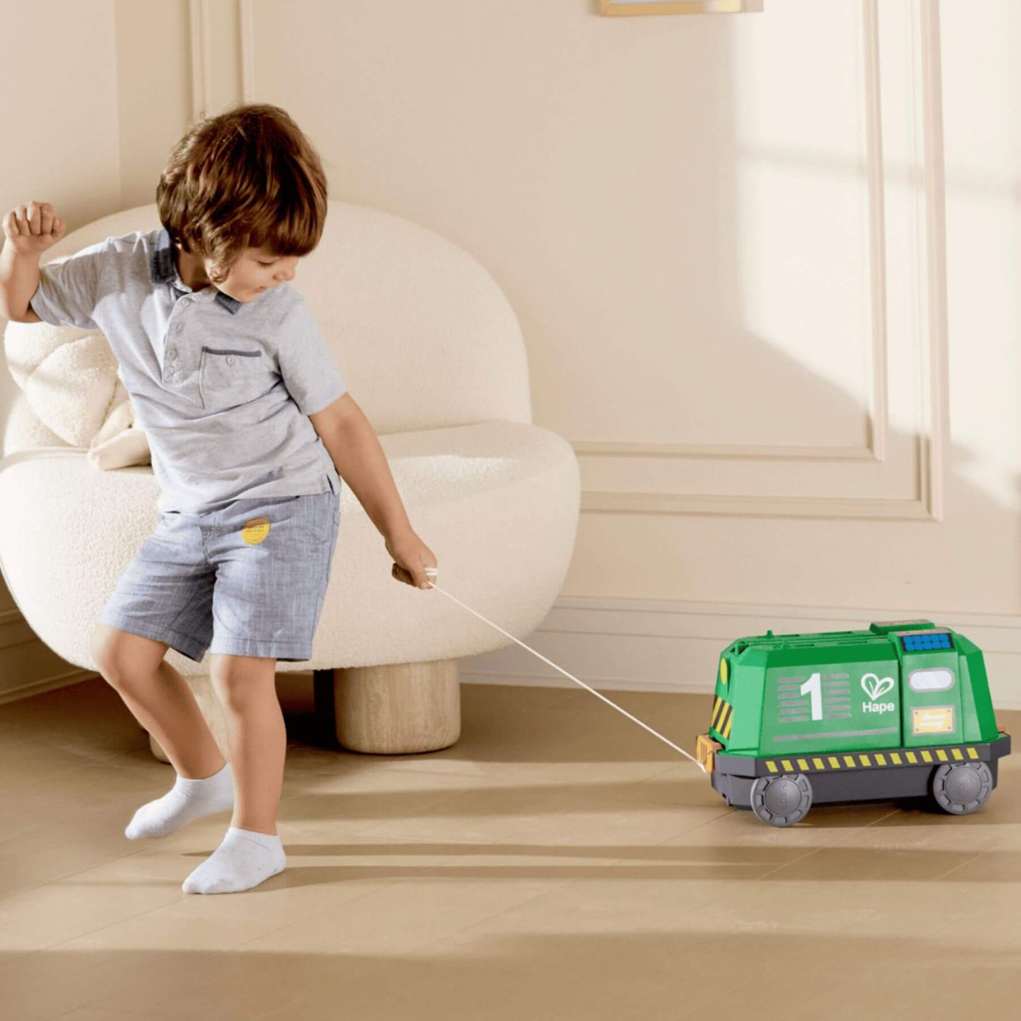 Child pulling Hape Eco Energy Train Bucket Set across a wooden floor.