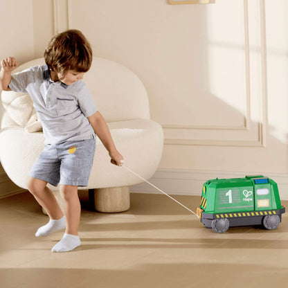 Child pulling Hape Eco Energy Train Bucket Set across a wooden floor.