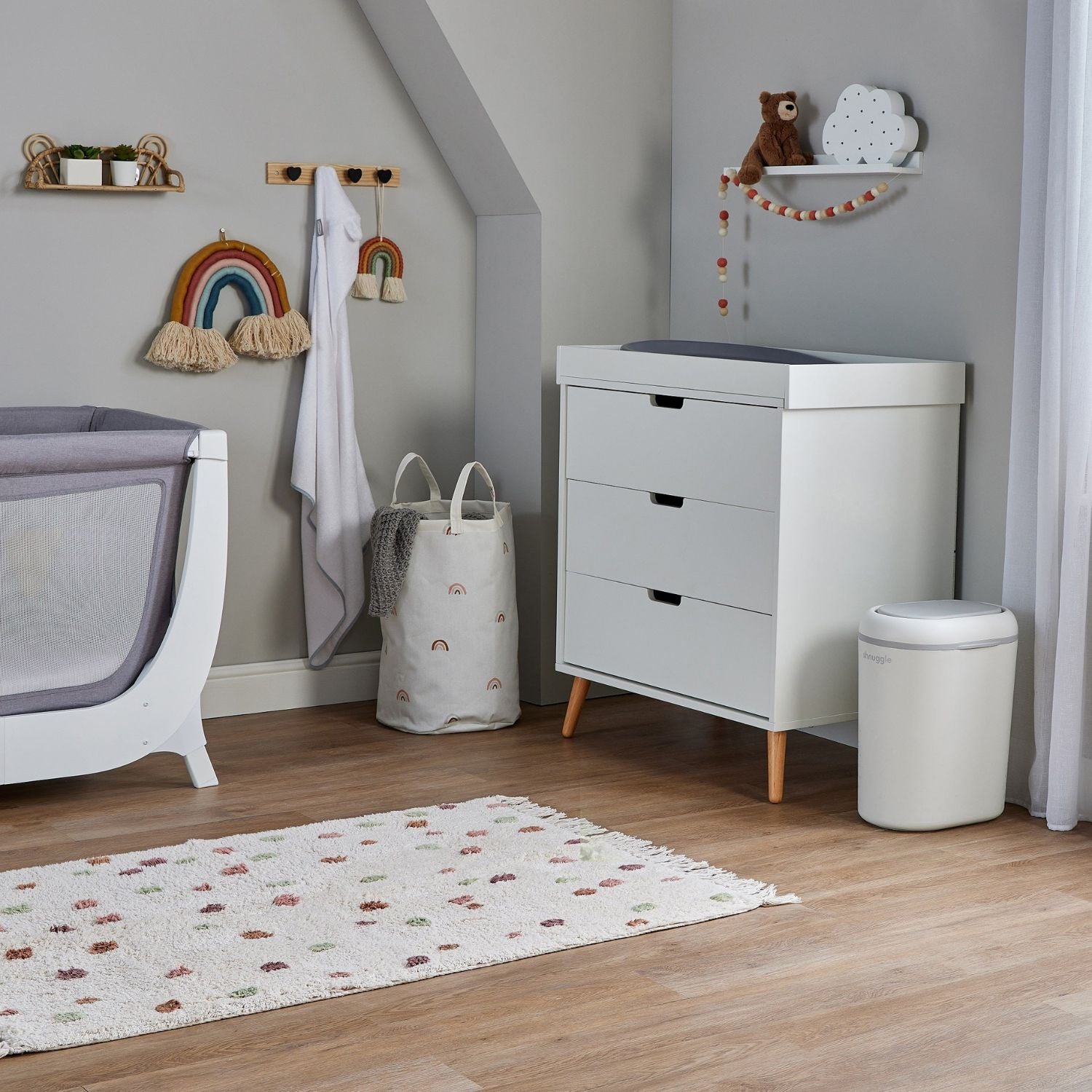 Nursery room with crib, changing table, and decorative elements on a wooden floor.