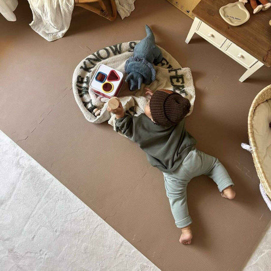 Child playing with toys on Eeveve Cinnamon - Play Mat in a room with furniture.