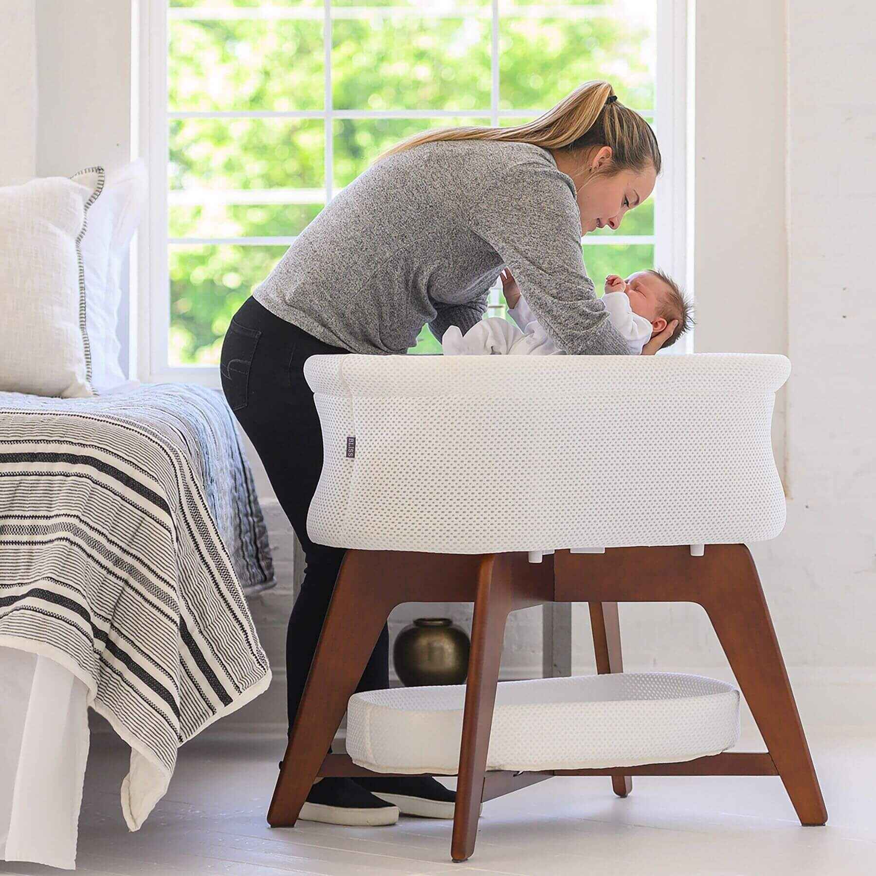 Mom Putting Baby in TruBliss Evi Smart Bassinet White