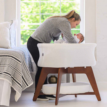 Mom Putting Baby in TruBliss Evi Smart Bassinet White