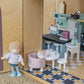 Toy kitchen set with doll and furniture on a checkered floor