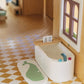 Miniature bathtub with toy faucet and bath bombs in a dollhouse bathroom.