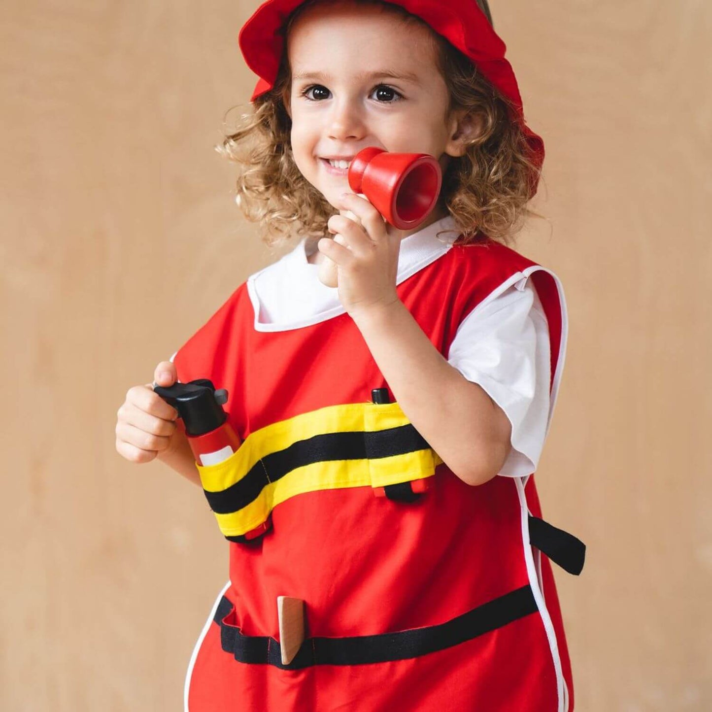 Child in PlanToys Fire Fighter Play Set against a beige background