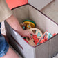 Child playing with colorful wooden toys inside a gray storage bin.