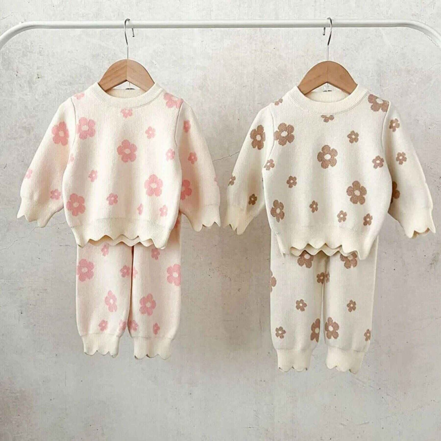 Two Flower Power Knitted Set hanging on a rack against a light background.