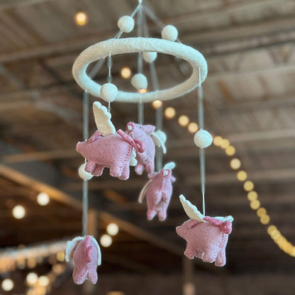 Ganapati Crafts Co. Felt Baby Mobile - Flying Pig hanging from a ceiling with blurred lights in the background