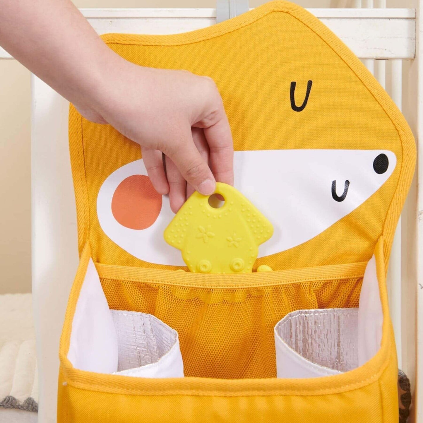 Forest Friends Hanging Organizer fox and a hand holding a yellow teether.