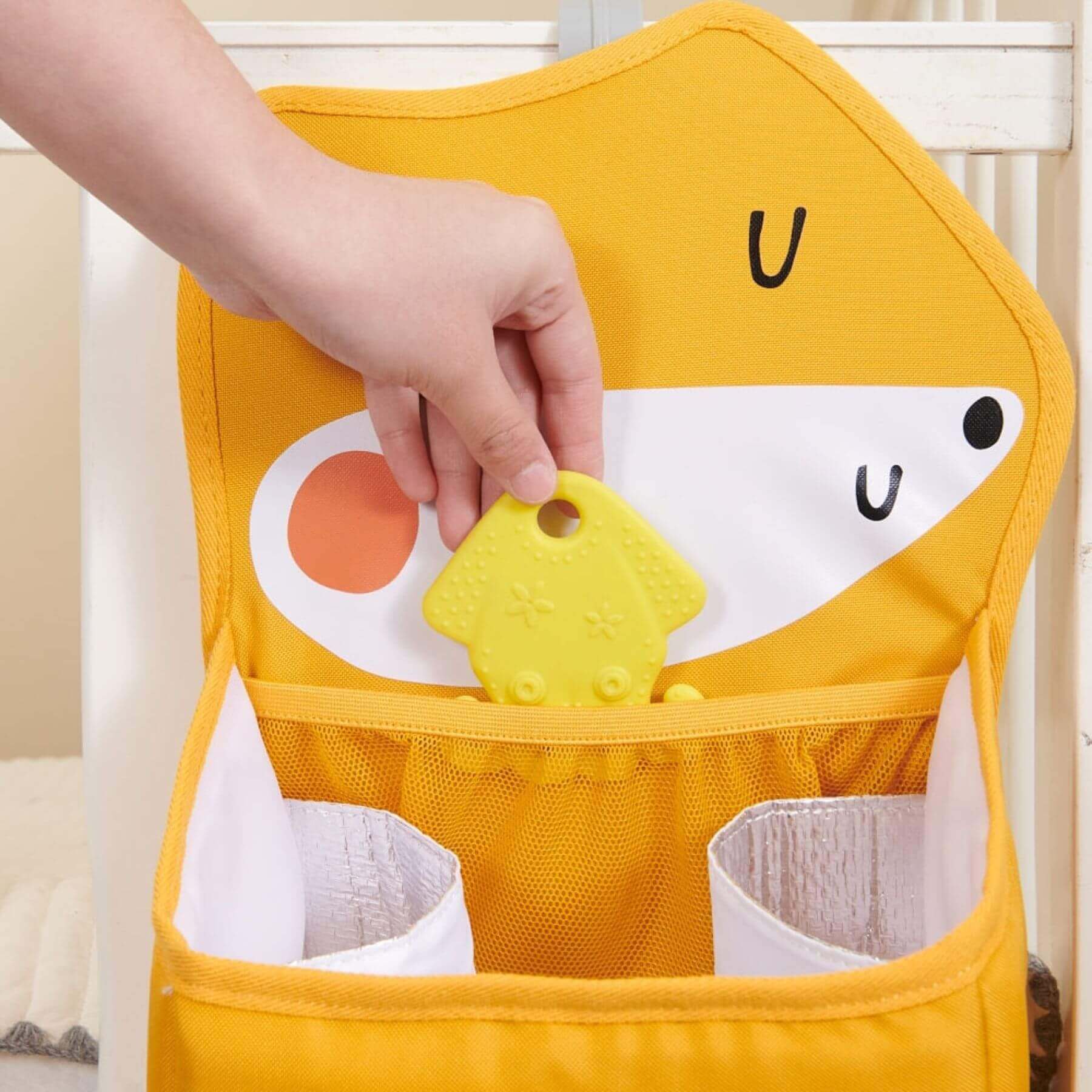Forest Friends Hanging Organizer fox and a hand holding a yellow teether.