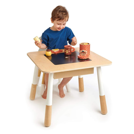 Child playing at Tender Leaf Forest Table with colorful toys on a white background