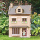 Tender Leaf Foxtail Villa with a toy girl standing in the doorway, set against a green outdoor background.