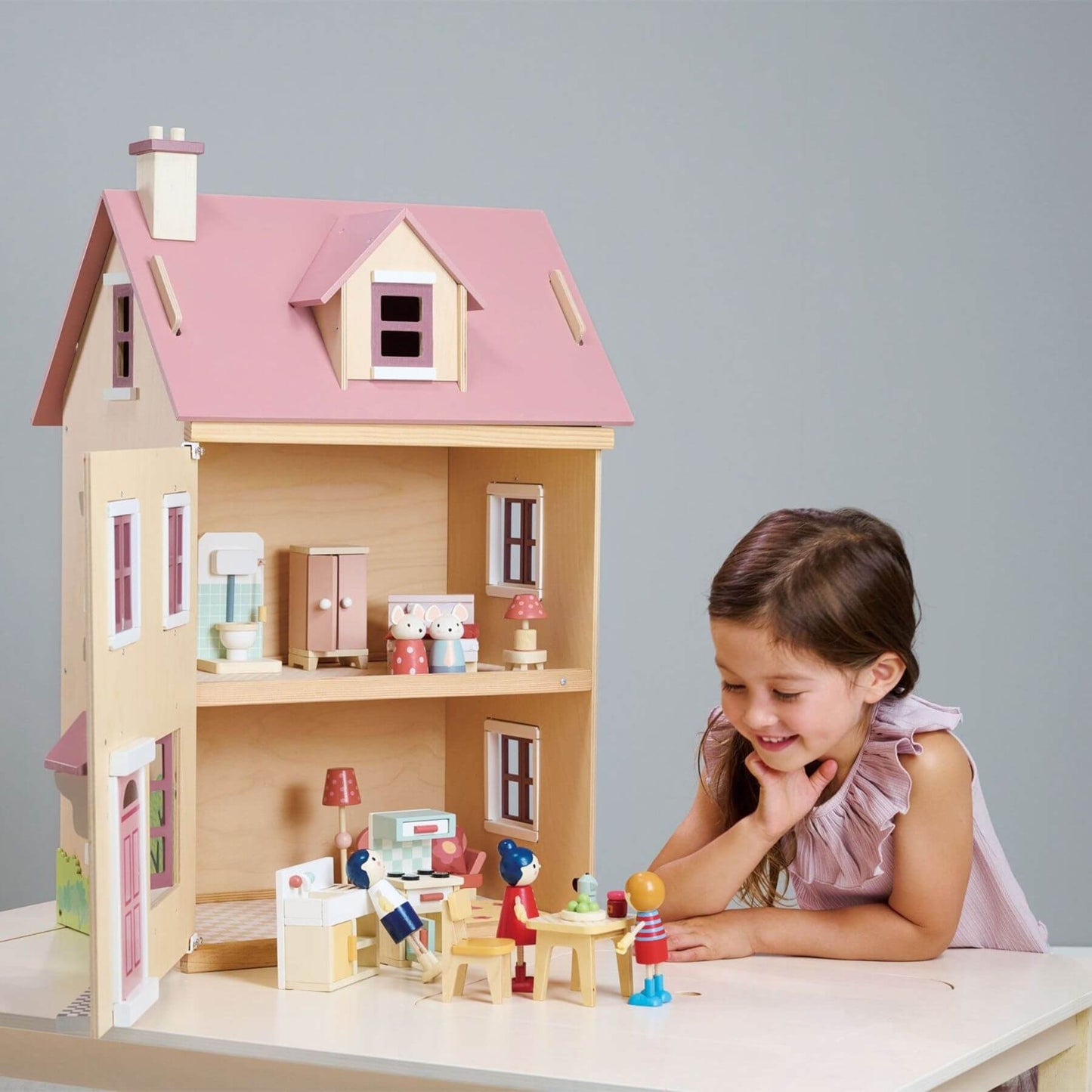 Child playing with Tender Leaf Foxtail Villa Pink and accessories on a table.