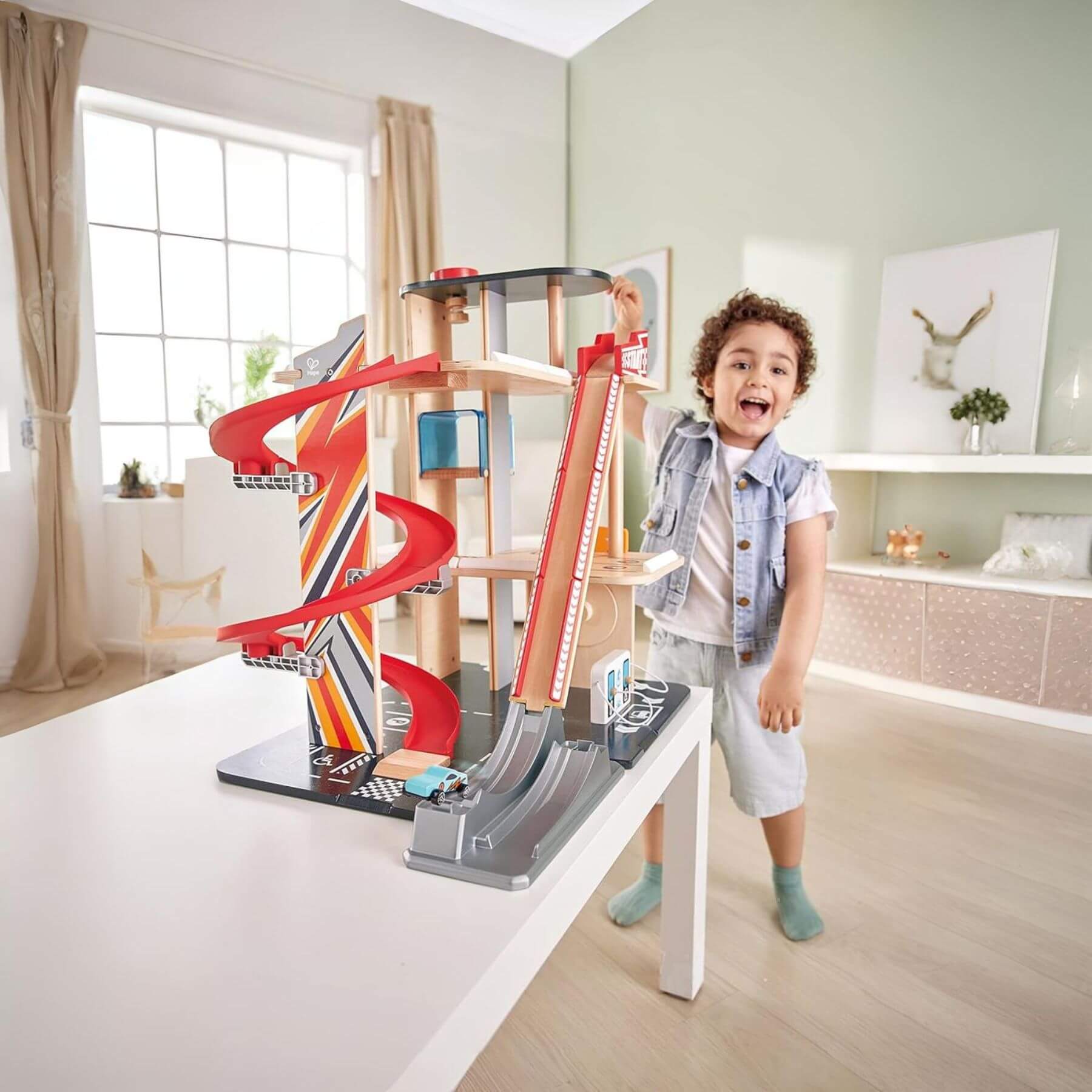 Child playing with Hape Gearhead Stunt Garage in a modern living room