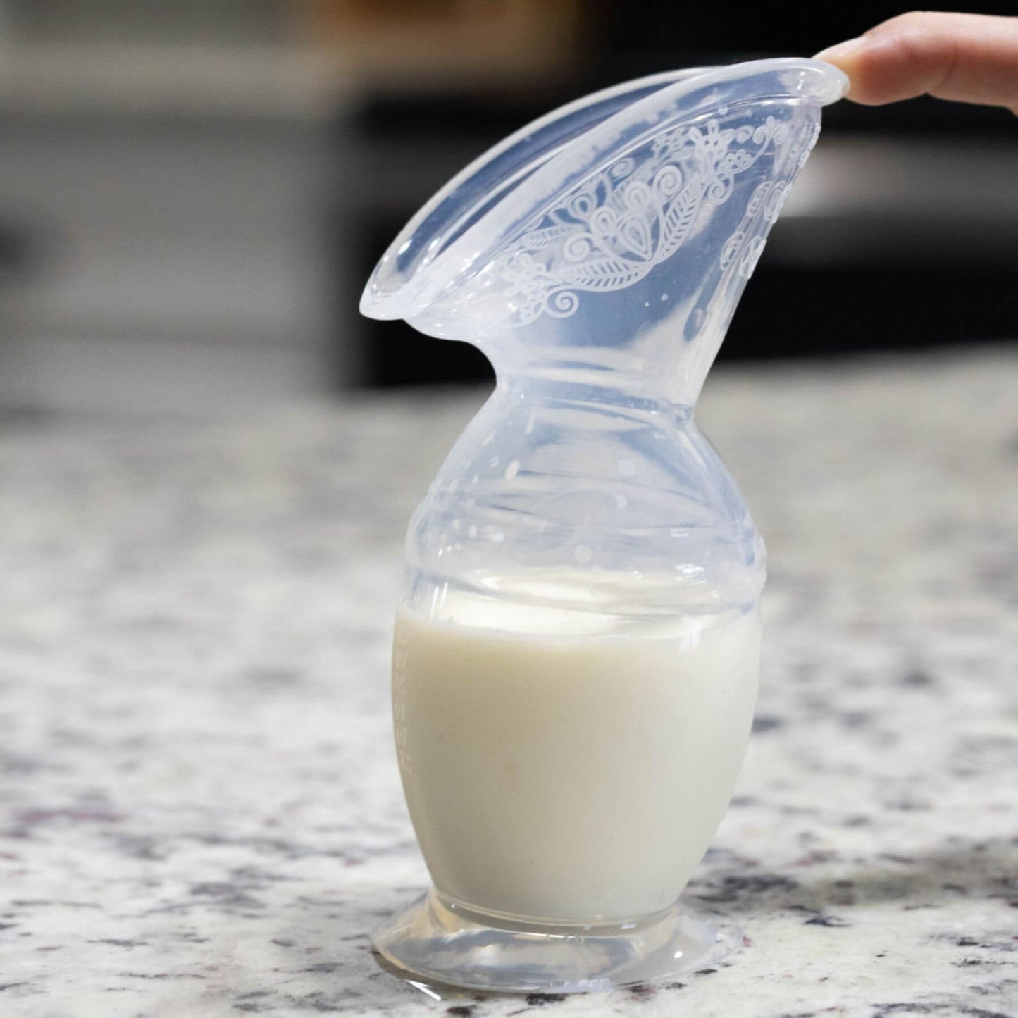 Haakaa Generation 2 Silicone Breast Pump with Suction Base 5 oz 1pk with milk on a marble surface