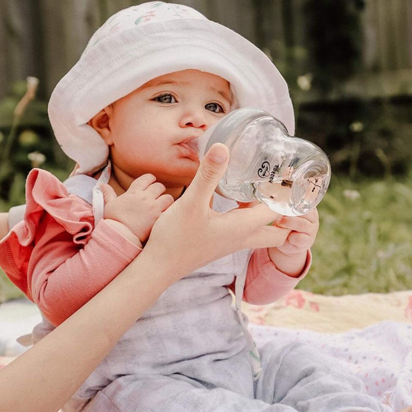 Baby being fed from Haakaa Generation 3 Glass Baby Bottle Grey with a blurred natural background