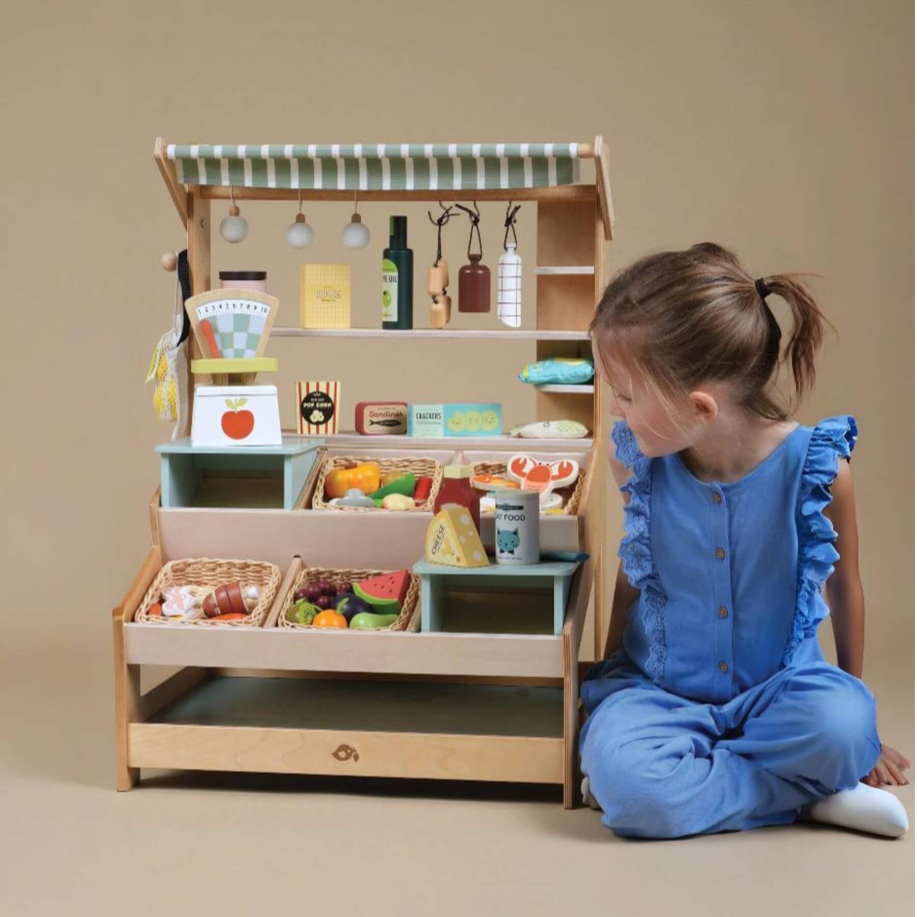 Child playing with Tender Leaf General Stores on a beige background