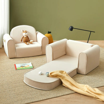 Tiny Land® GentleSnug Kid Chair Beige White with toys and a book on a wooden floor against a green wall.