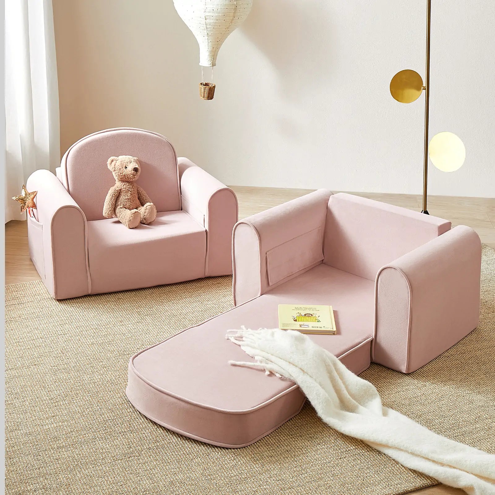2 Tiny Land® GentleSnug Kid Chair Pink with a teddy bear and blanket in a room.