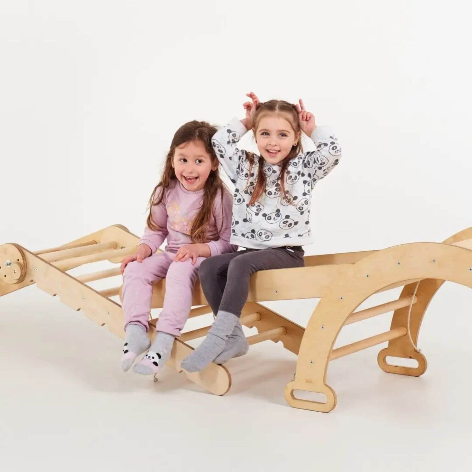 Two children sitting on a wooden climbing set