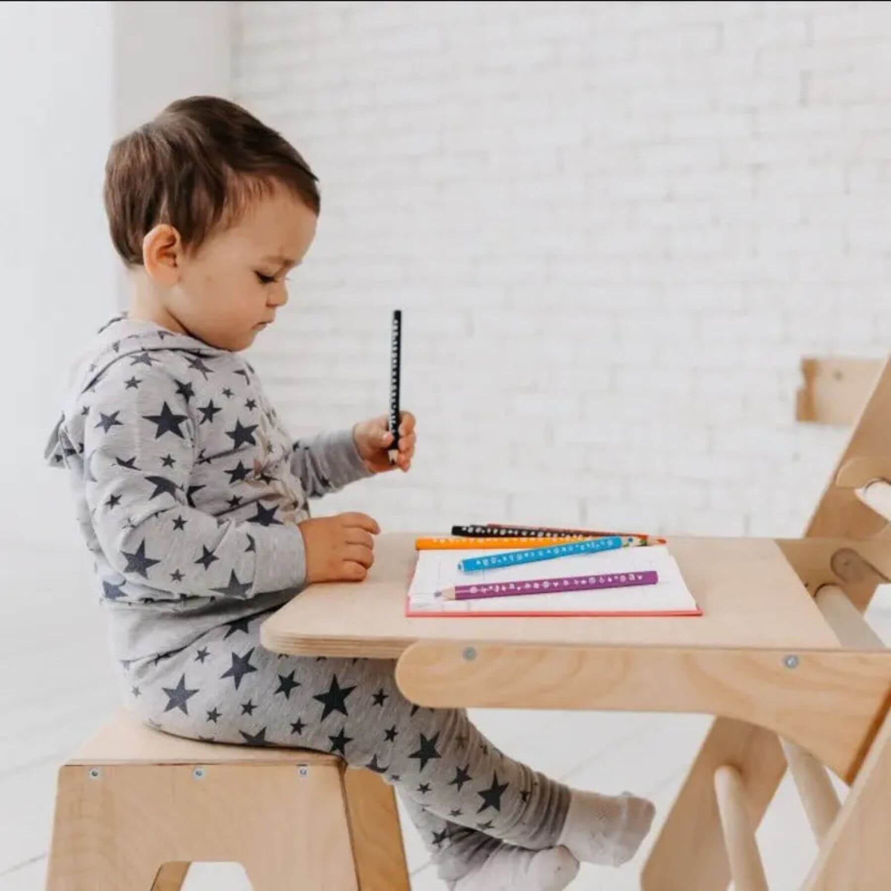 Child sitting a wooden chair, using Goodevas Art Addition on the Triangle Ladder