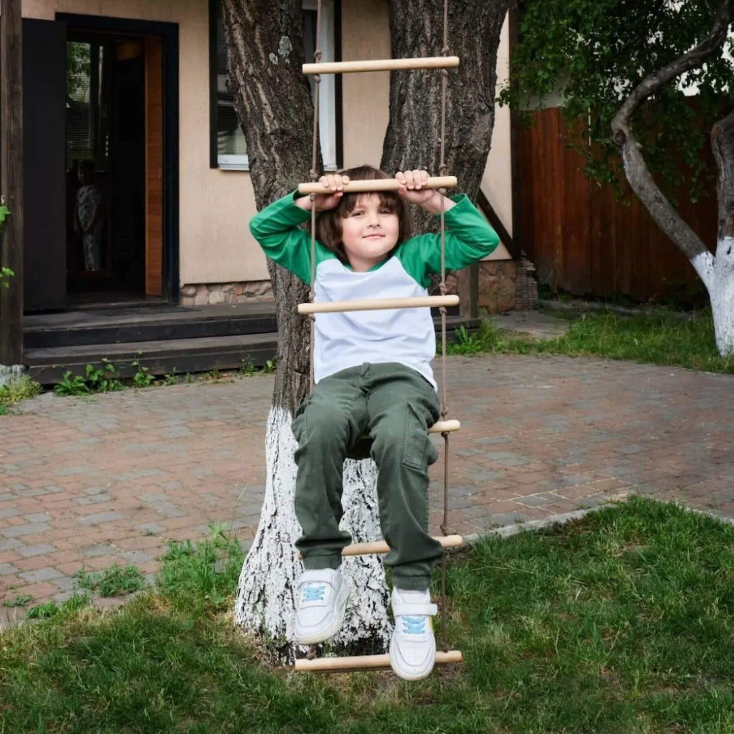 Child sitting on Goodevas Climbing Rope Ladder in a backyard