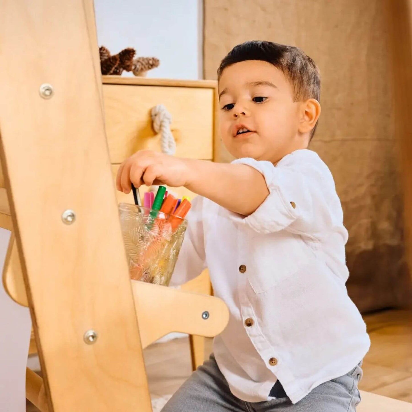 Child playing with colorful markers in a wooden chair