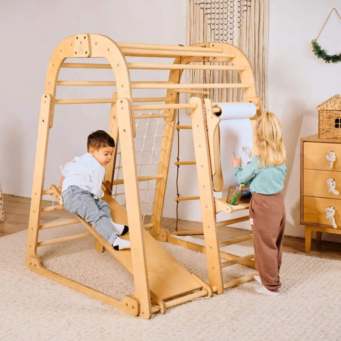Two children playing on Goodevas Indoor Pplayground in a room with a dresser and decorative items.