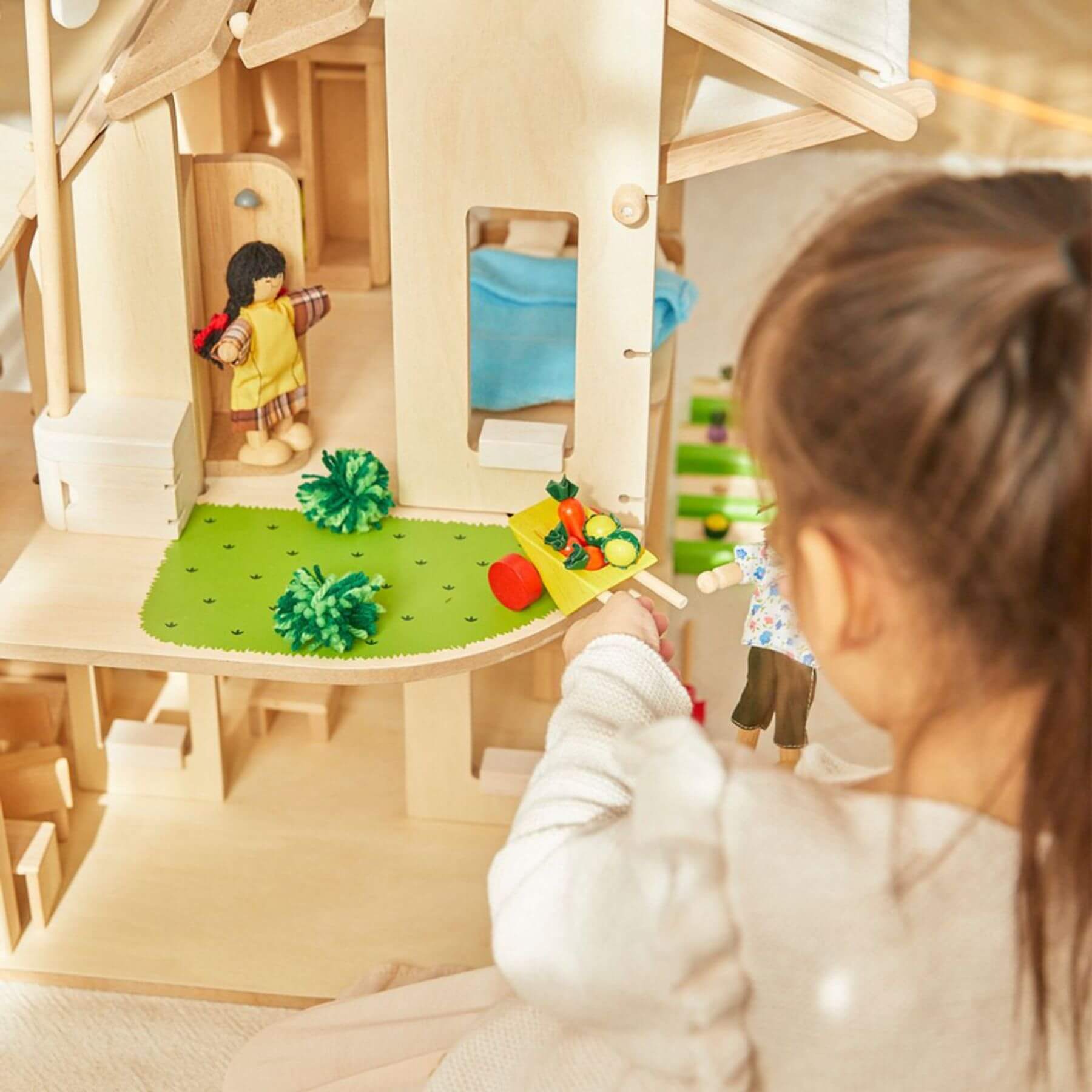 Child playing with PlanToys Green Dollhouse With Furniture indoors