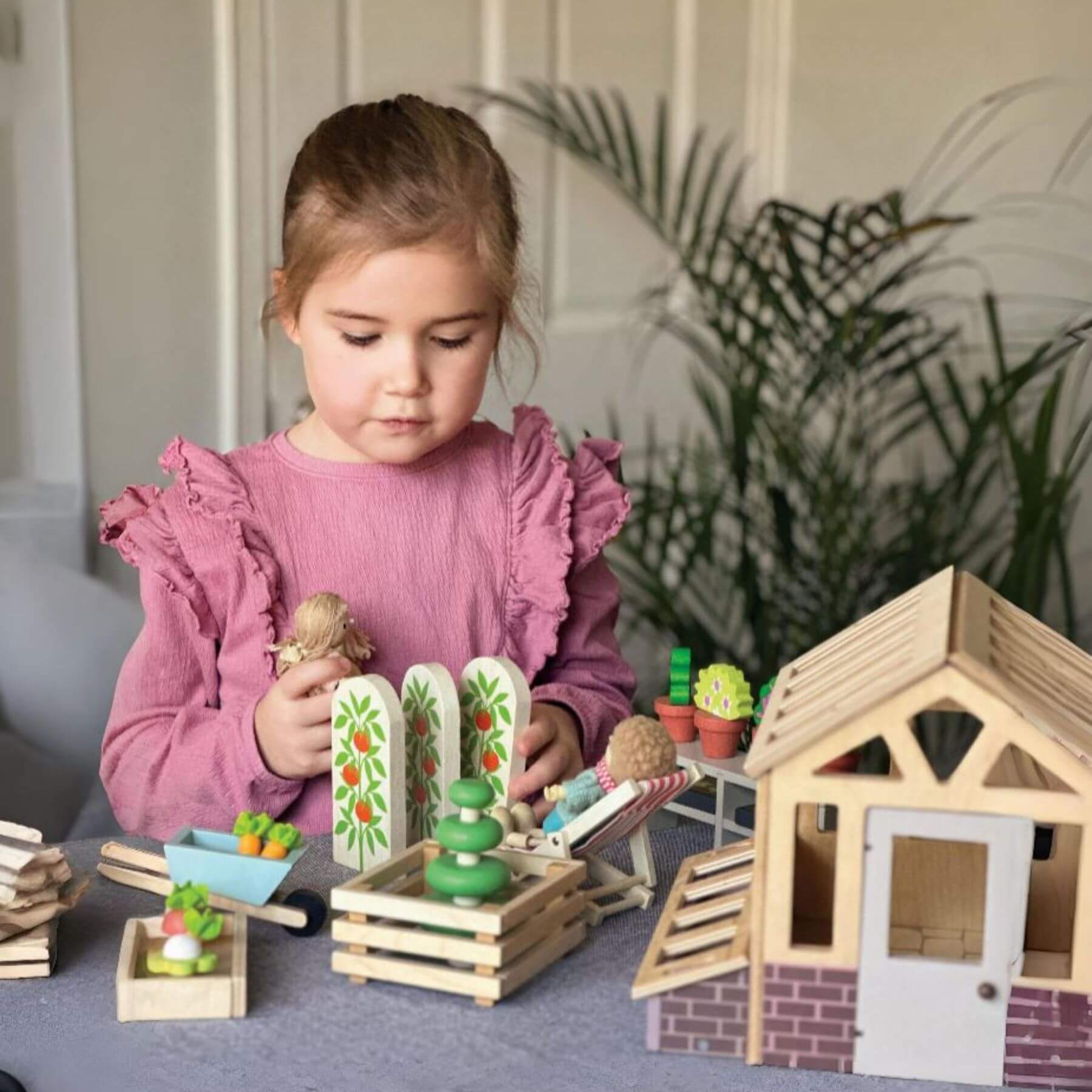 Young girl playing with Tender Leaf Greenhouse and Garden Set on a table