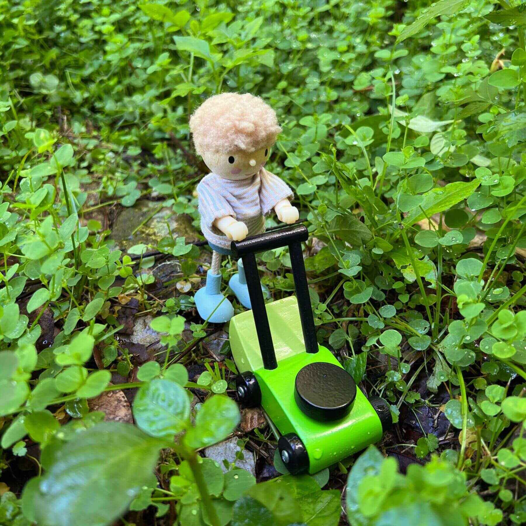 Small toy figure on a green toy car in a grassy area