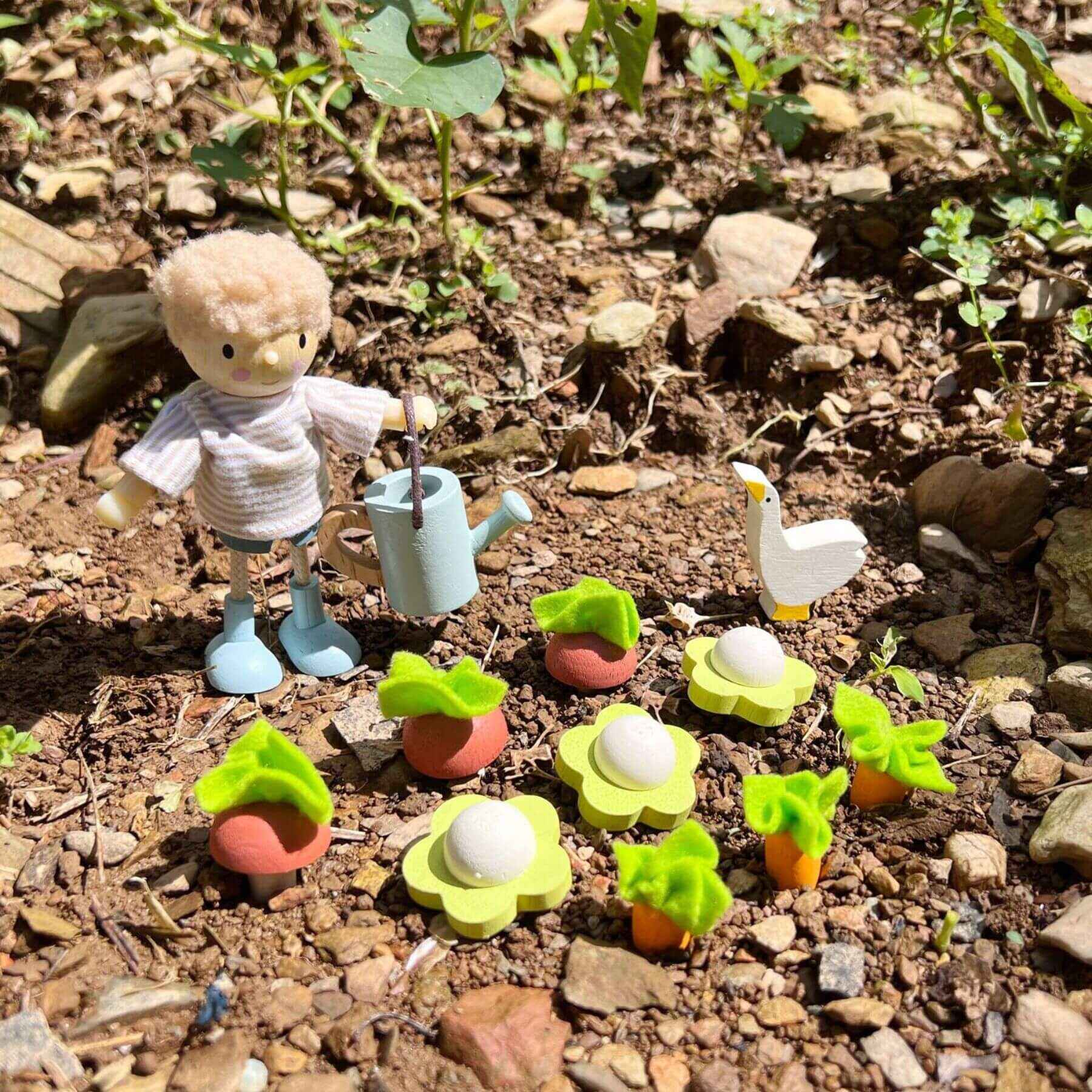 Miniature garden scene with figurines on a dirt surface