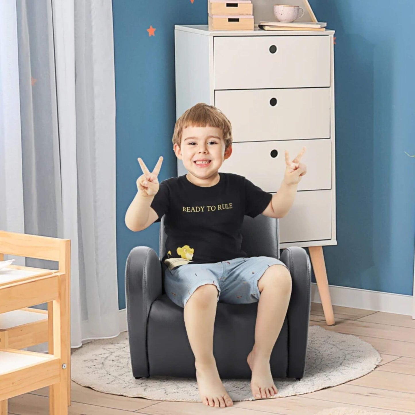 Child sitting on Qaba PU Leather Kids Sofa Rocking Chair Grey in a room with a blue wall and white dresser.